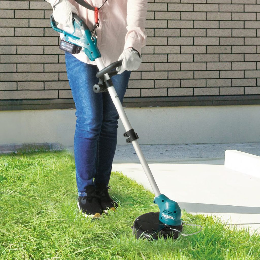 MAKITA Ruohotrimmeri CXT. Kuvassa henkilö trimmaamassa nurmikkoa Ruohotrimmeri CXT:n avulla.