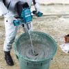 MAKITA Sekoituskone XGT. Kuvassa henkilö sekoittamassa betonia paljussa Sekoituskone XGT:n avulla.