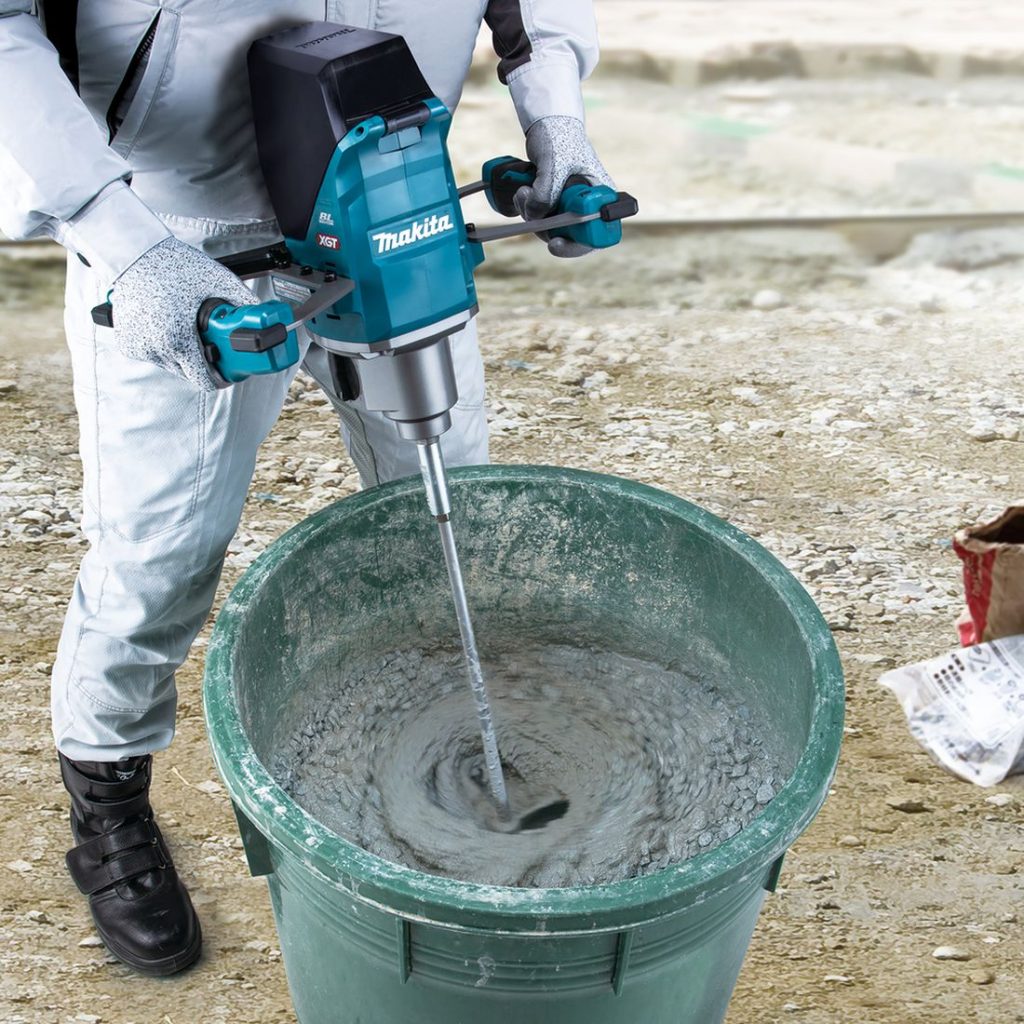MAKITA Sekoituskone XGT. Kuvassa henkilö sekoittamassa betonia paljussa Sekoituskone XGT:n avulla.