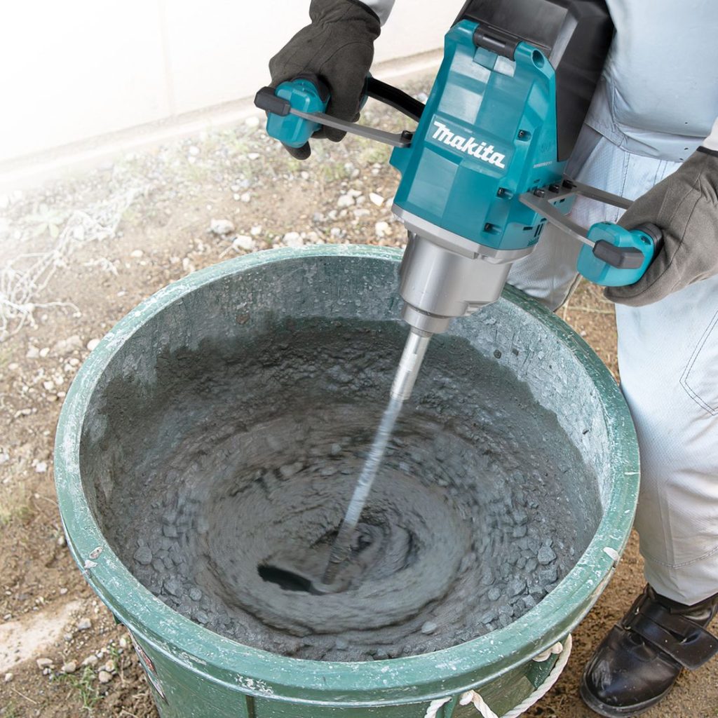 MAKITA Sekoituskone XGT. Kuvassa henkilö sekoittamassa betonia paljussa Sekoituskone XGT:n avulla.