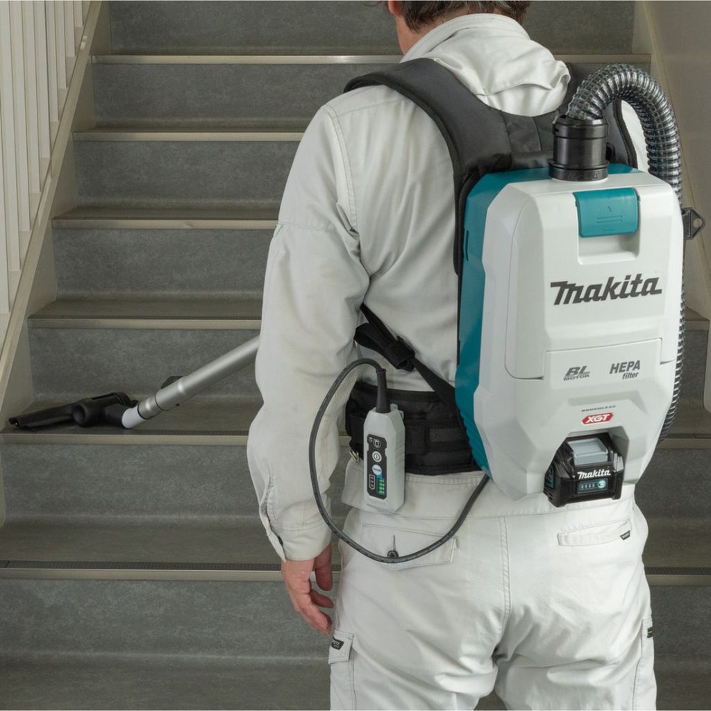 MAKITA Reppuimuri XGT. Kuvassa henkilö imuroimassa rappukäytävän portaita Reppuimuri XGT:n avulla.