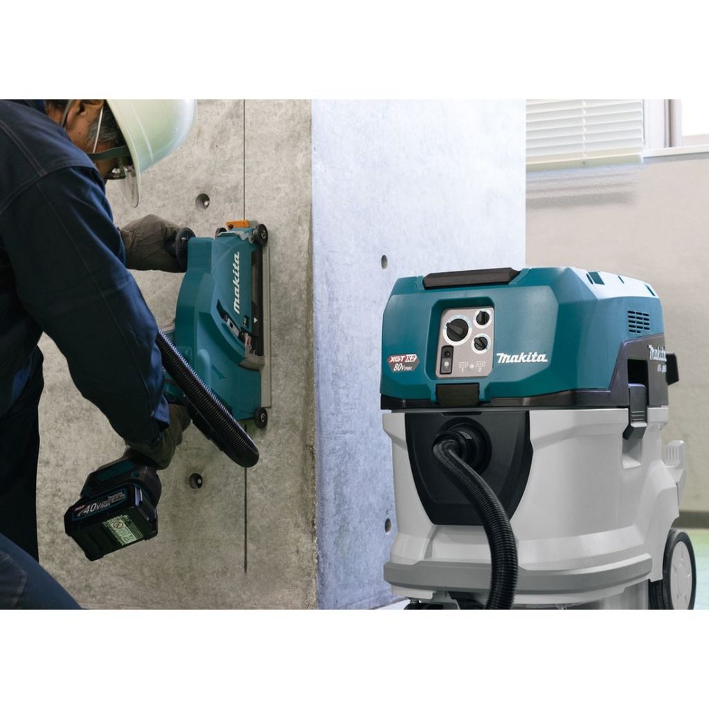 MAKITA Märkä- / kuivaimuri XGT VC006GMZ01. Kuvassa henkilö sahaamassa betoniseinää laikkaleikkurin avulla märkä-/kuivaimuri liitettynä laikkaleikkuriin.