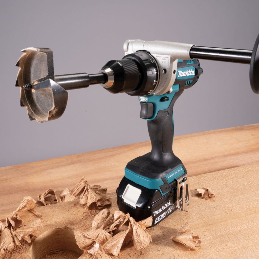 MAKITA Porakone LXT. Kuvassa porakone LXT oikealta etuyläviistosta työtason päällä reikäsahanterä kiinnitettynä porakoneeseen.