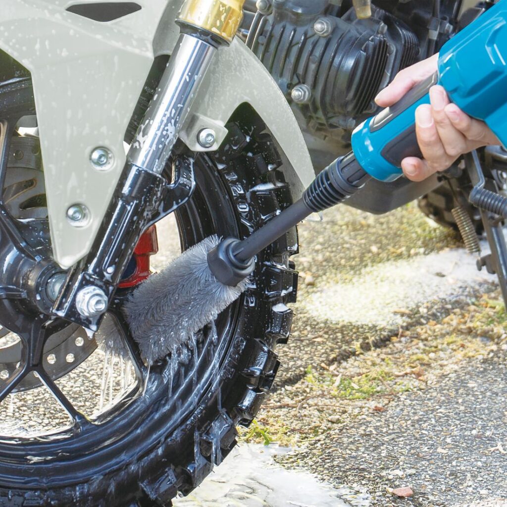 MAKITA Akkupainepesuri LXT. Kuvassa henkilö pesemässä moottoripyörän takalokaria akkupainepesurin avulla.
